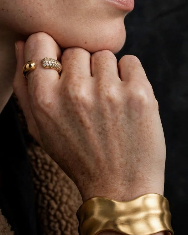 Close-up of the Halo Pavé ring and Contour cuff in gold, worn