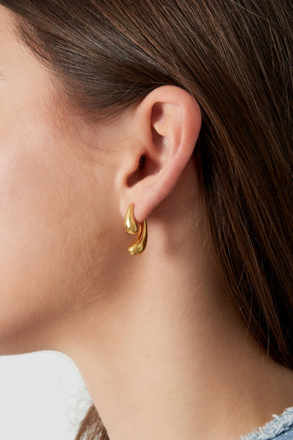 Gold hoop earring worn by a person with brown hair.