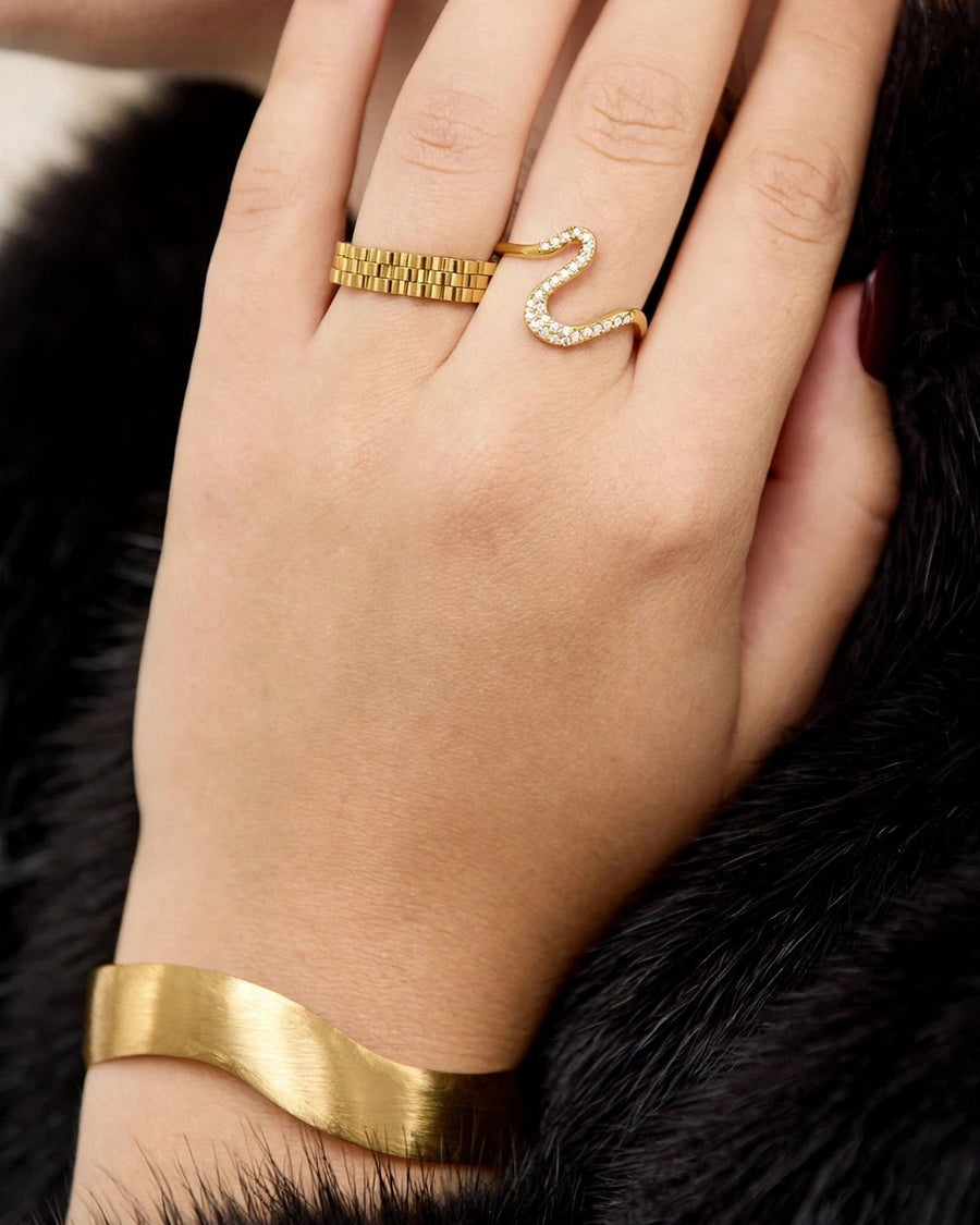 Close-up of hand wearing two gold rings and the Contour cuff